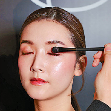 先用眼影組合的霧面淺啡色眼影掃上整個眼窩打底，再混合細緻金色珠光蜜桃粉紅色與閃亮蛋白石色提亮，營造立體感。