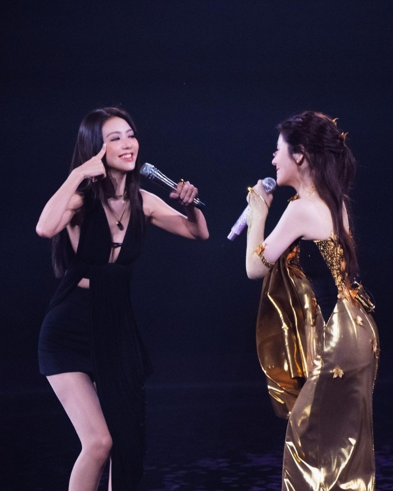 照片中，薛凱琪身穿一件黑色超低胸交叉綁帶背心配黑色短褲，同女星張碧晨手拖手同臺合唱。