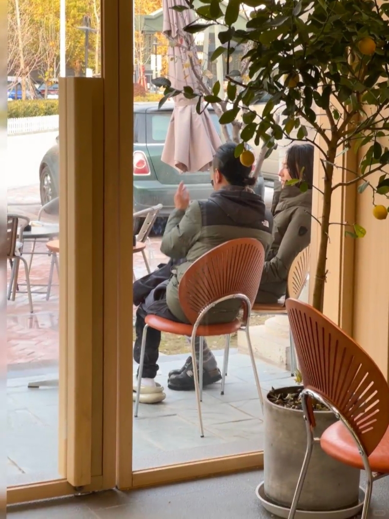 梁洛施與馬浴柯均穿著軍綠色羽絨，二人坐在店外的椅子上閑聊。