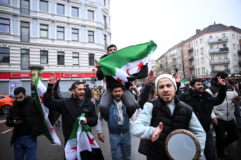 2024年12月8日，德國柏林敘利亞反抗軍宣布推翻敘利亞阿薩德政府后，人們舉著敘利亞反對派旗幟聚集在柏林一處廣場。 路透社