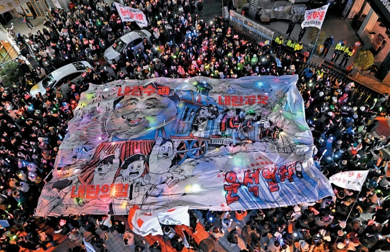 首爾示威者在執政國民力量黨總部外舉行「彈劾燭光集會」，展示諷刺總統尹錫悅的漫畫。