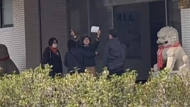 林岱樺與干員在南機站門口爆拉扯，一高舉標語激動喊“政治、司法干預初選”遭阻擋。