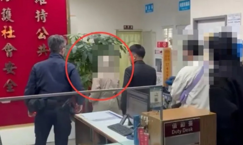 梁妻（紅圈處）做完筆錄低頭不語離開警局。（翻攝中天新聞）